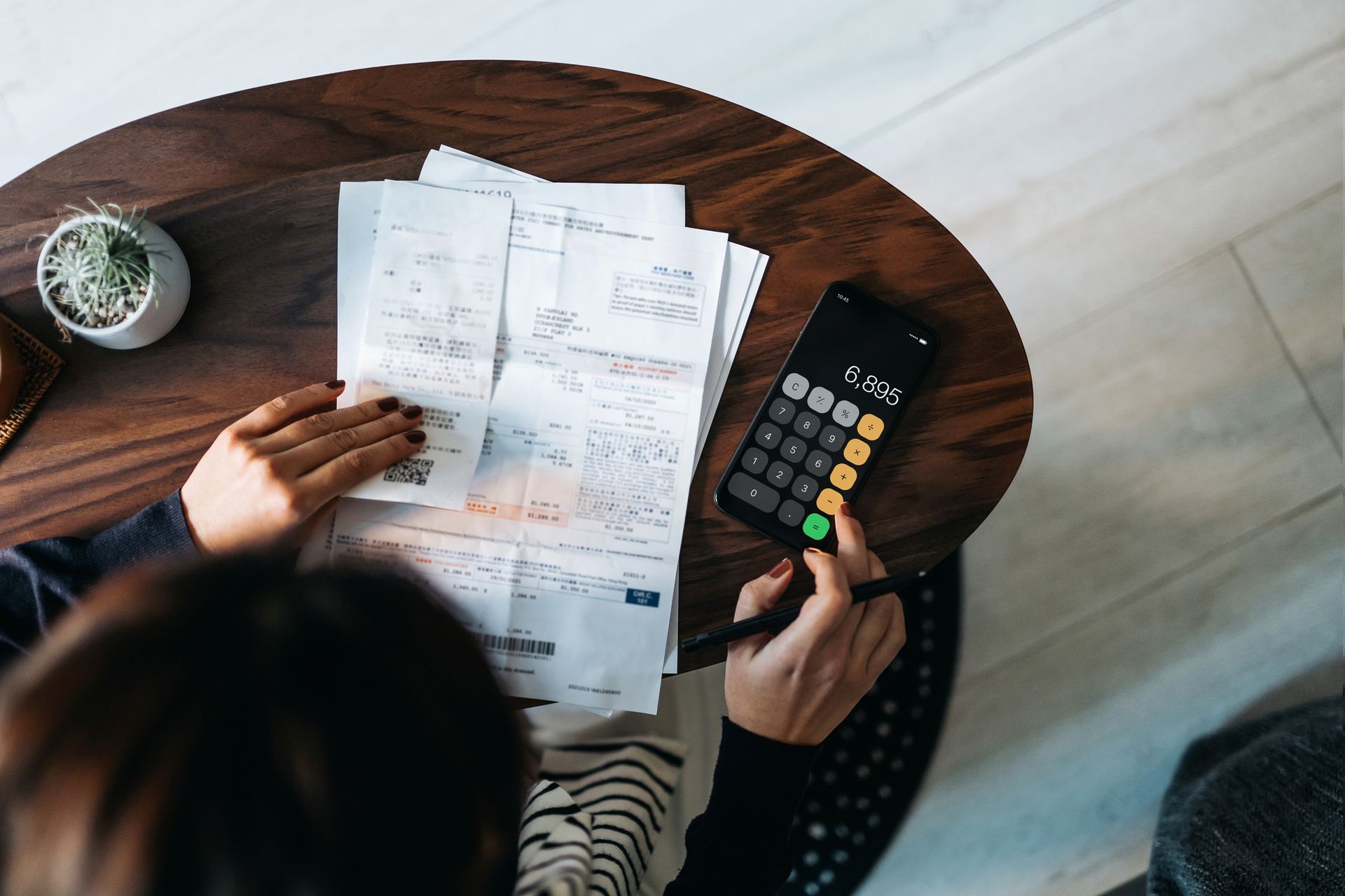 A person is sitting at a table using a calculator.