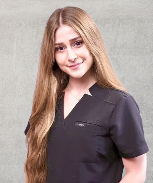 A woman with long blonde hair is wearing a black scrub top.