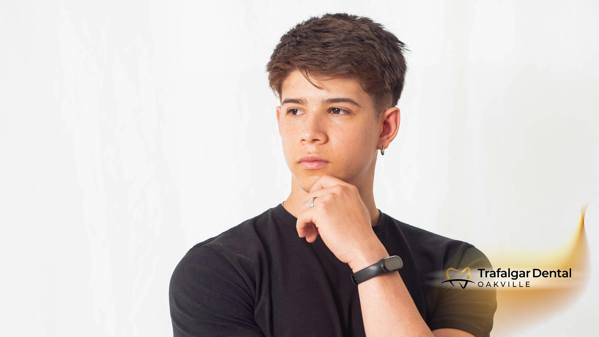 Young person with short, dark hair, wearing a black shirt, resting chin on hand, looking off to the side.