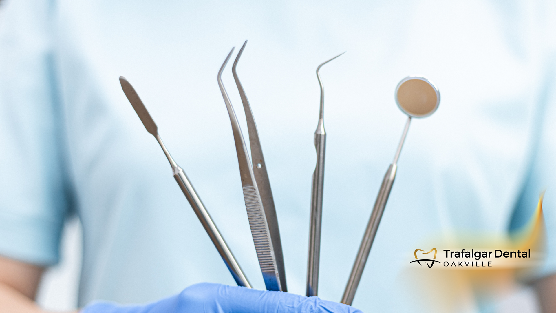A dentist is holding a bunch of dental instruments in his hand.