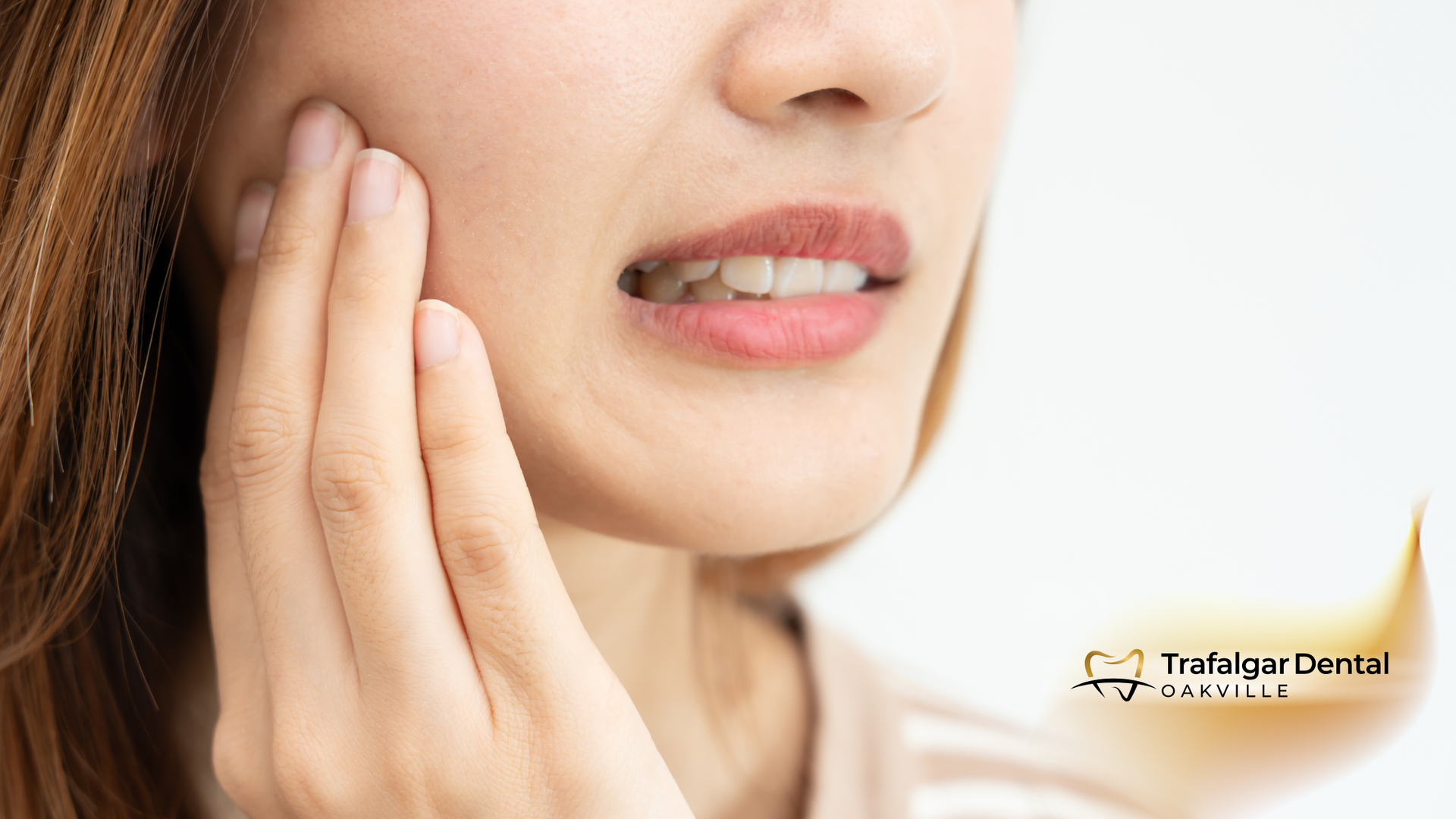 Woman holding cheek in pain, possibly due to a dental issue.