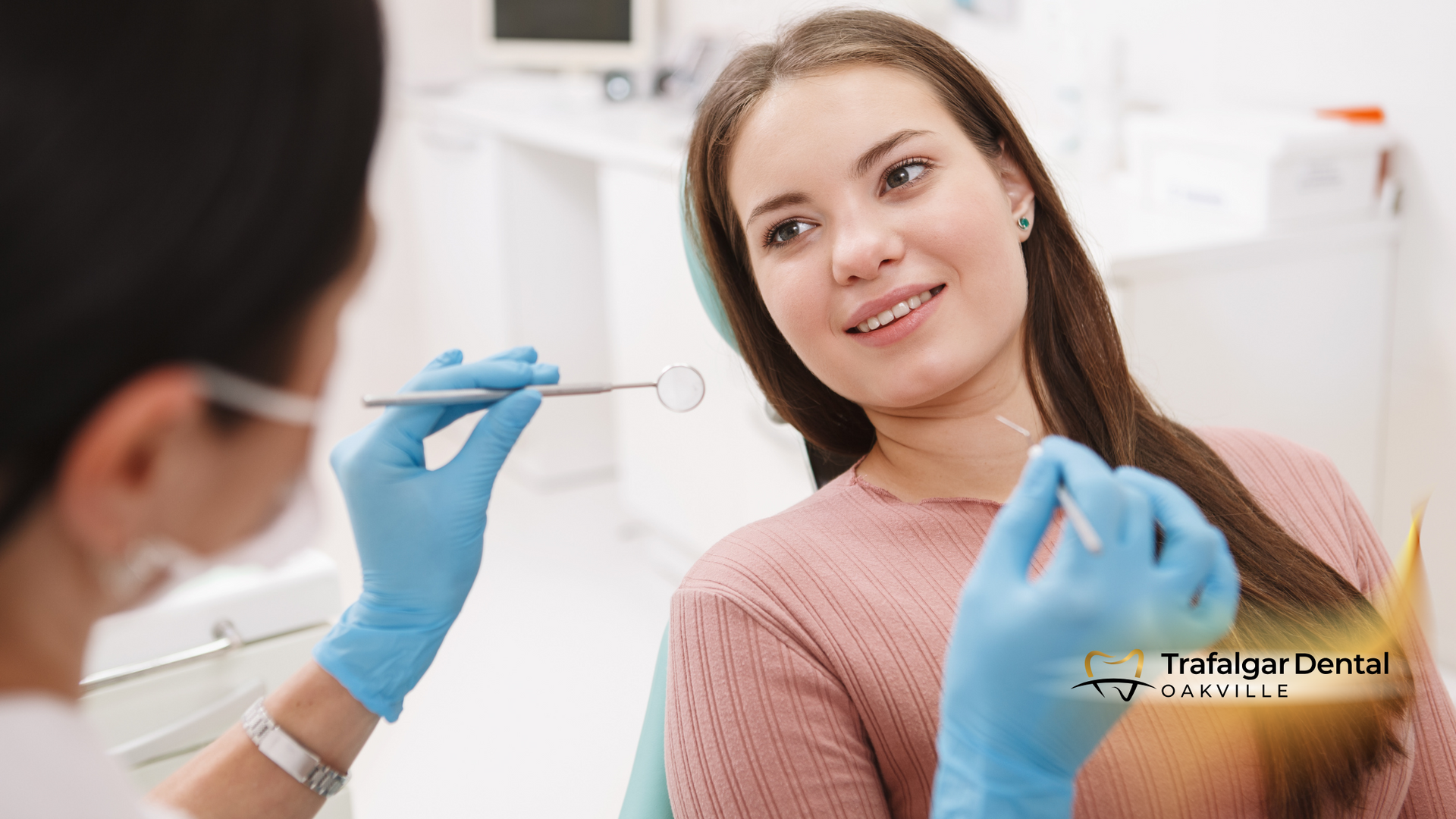 Dentist examining a smiling woman's teeth in a dental office setting. Blue gloves, instruments.