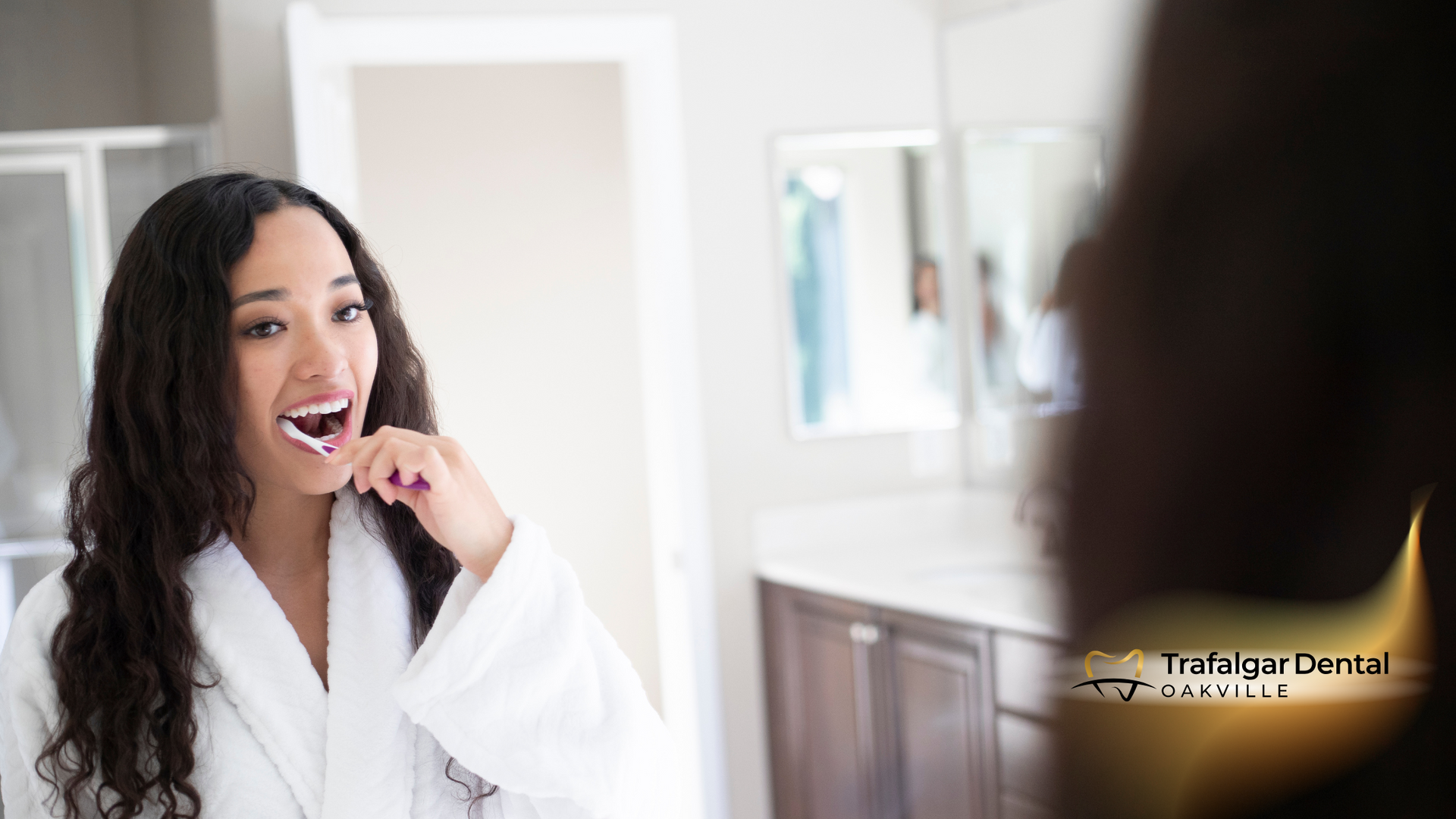 A woman is brushing her teeth in front of a mirror in a bathroom.