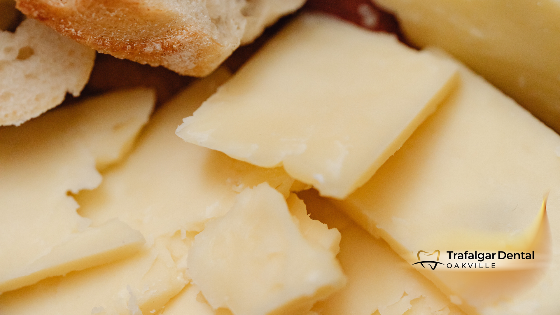 Close-up of sliced yellow cheese with bread, likely part of a snack or appetizer.