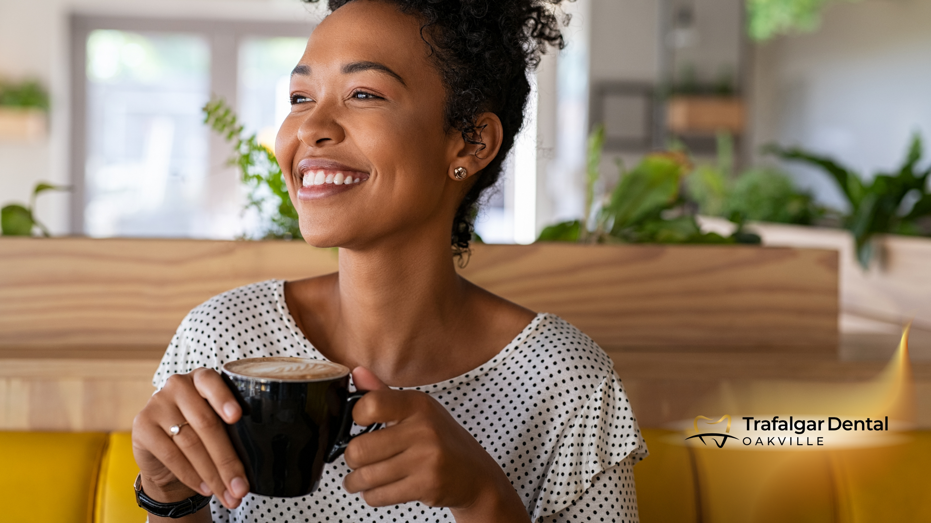 Woman with coffee smiles, in a cafe, looking content.