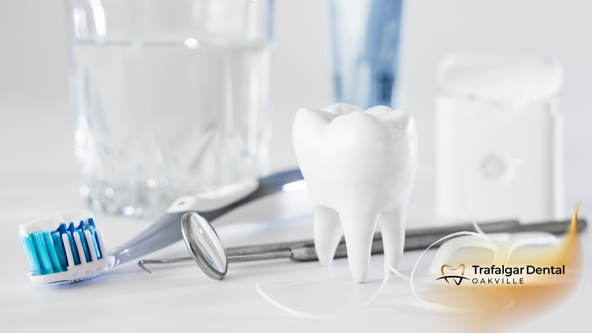 A tooth , a toothbrush , a mirror , and a glass of water are on a table.