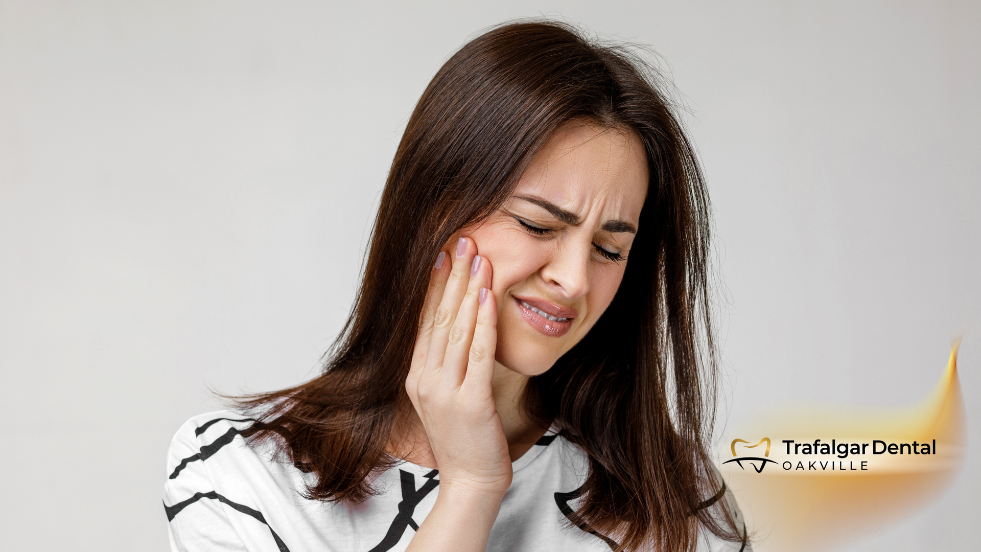Woman with hand on cheek, showing pain from toothache.