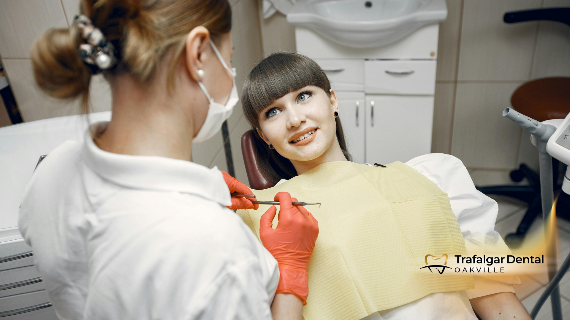 A woman is sitting in a dental chair getting her teeth examined by a dentist.