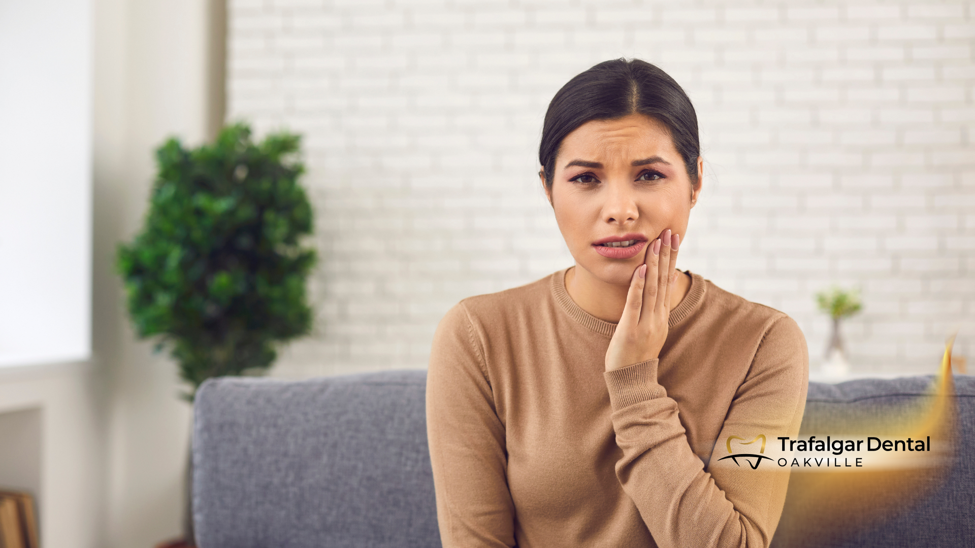 A woman is sitting on a couch with a toothache.