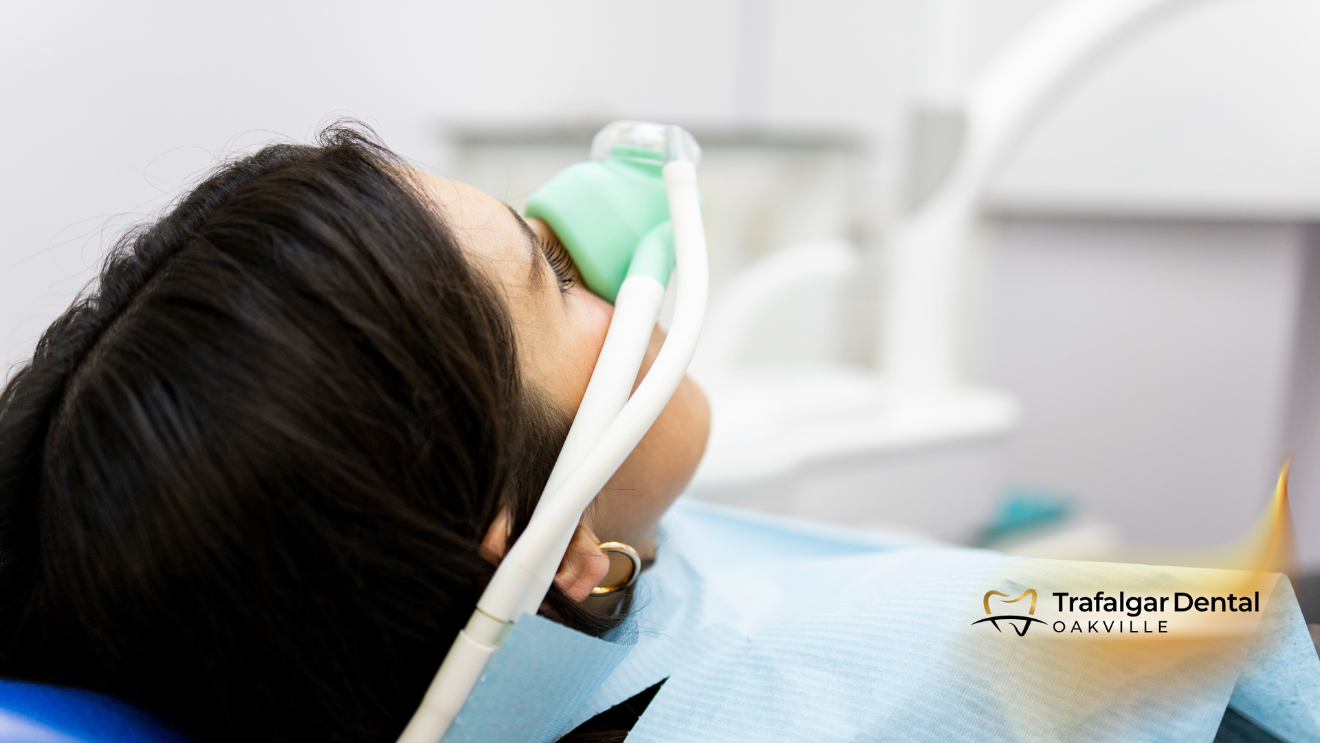 A woman is laying in a dental chair with an oxygen mask on her face.