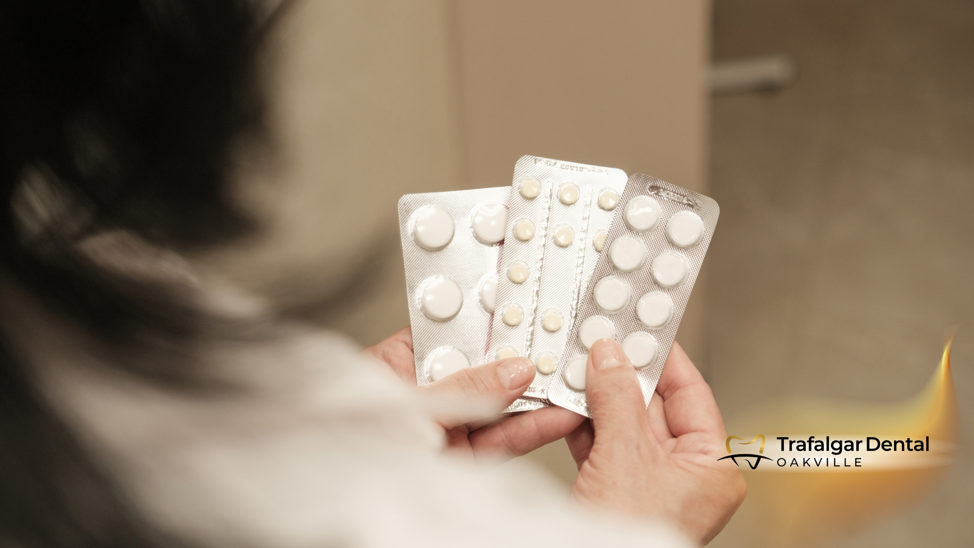 Person holding several blister packs of white pills.