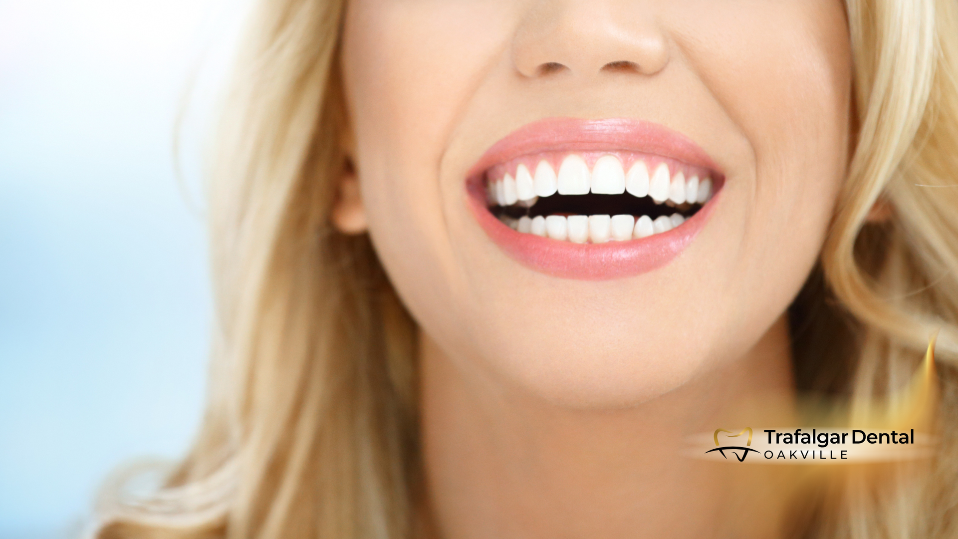 Woman smiling, showing perfect white teeth, blonde hair, soft pink lips, blue background.