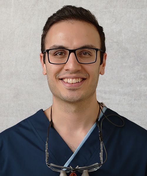 A woman with long blonde hair is wearing a black scrub top.
