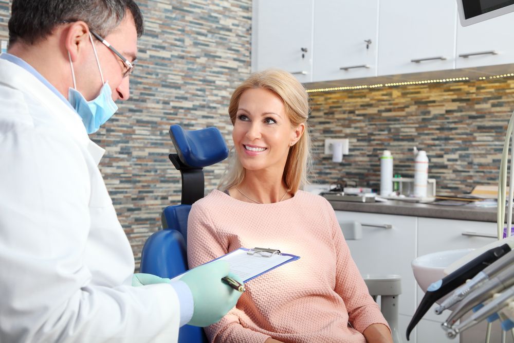 Dentist examining a patient's teeth with dental tools in a bright office setting.