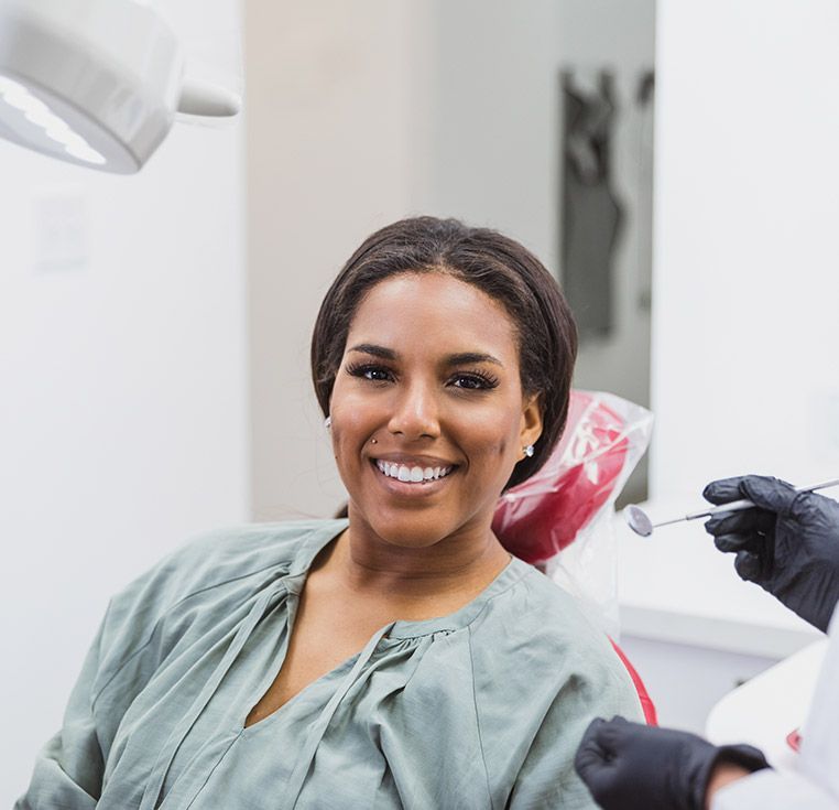 A woman is smiling while sitting in a dental chair.