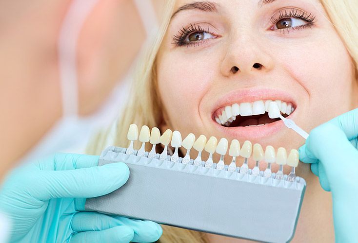 A woman is getting her teeth whitened by a dentist.
