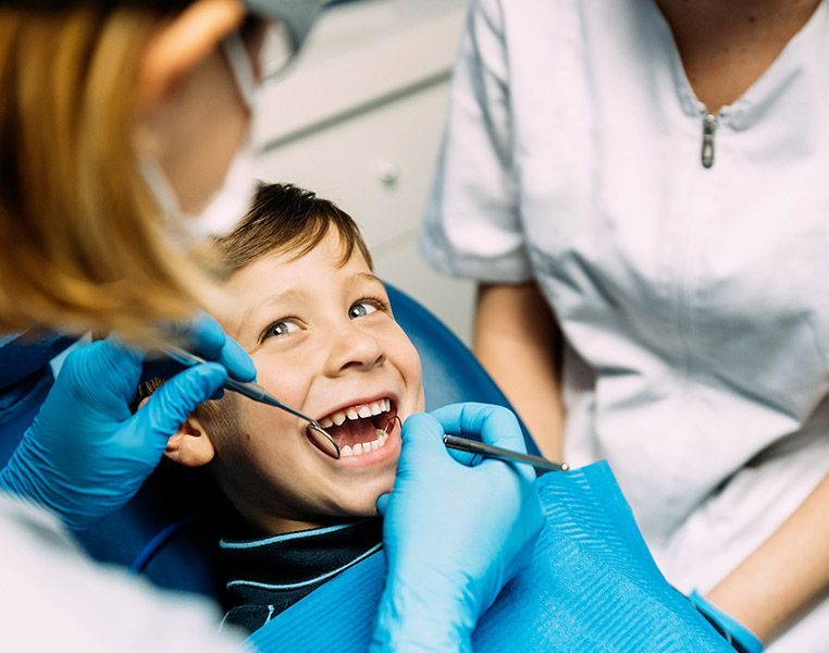 A young boy is getting his teeth examined by a dentist.