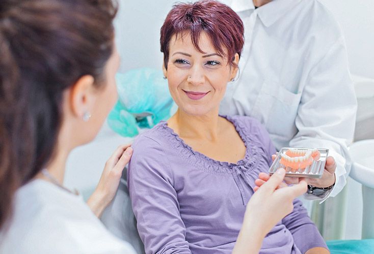 A woman is sitting in a dental chair talking to a dentist.