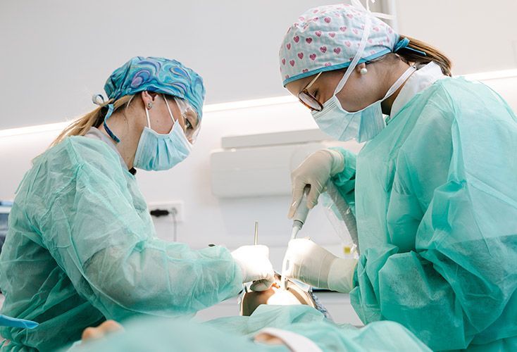 Two female surgeons are operating on a patient in an operating room.