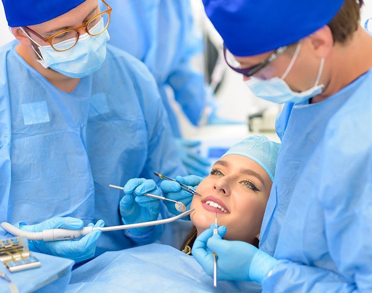 A woman is getting her teeth examined by two dentists in a dental office.