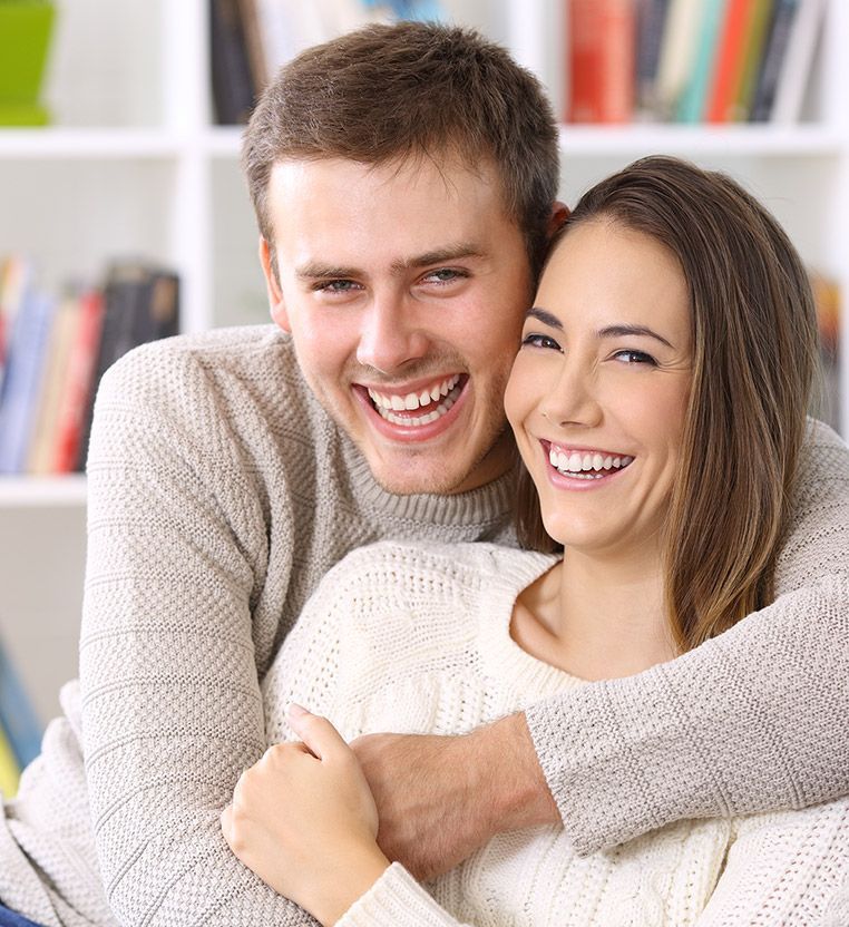 A man and a woman are hugging each other and smiling.