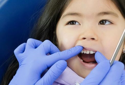 A little girl is getting her teeth examined by a dentist.