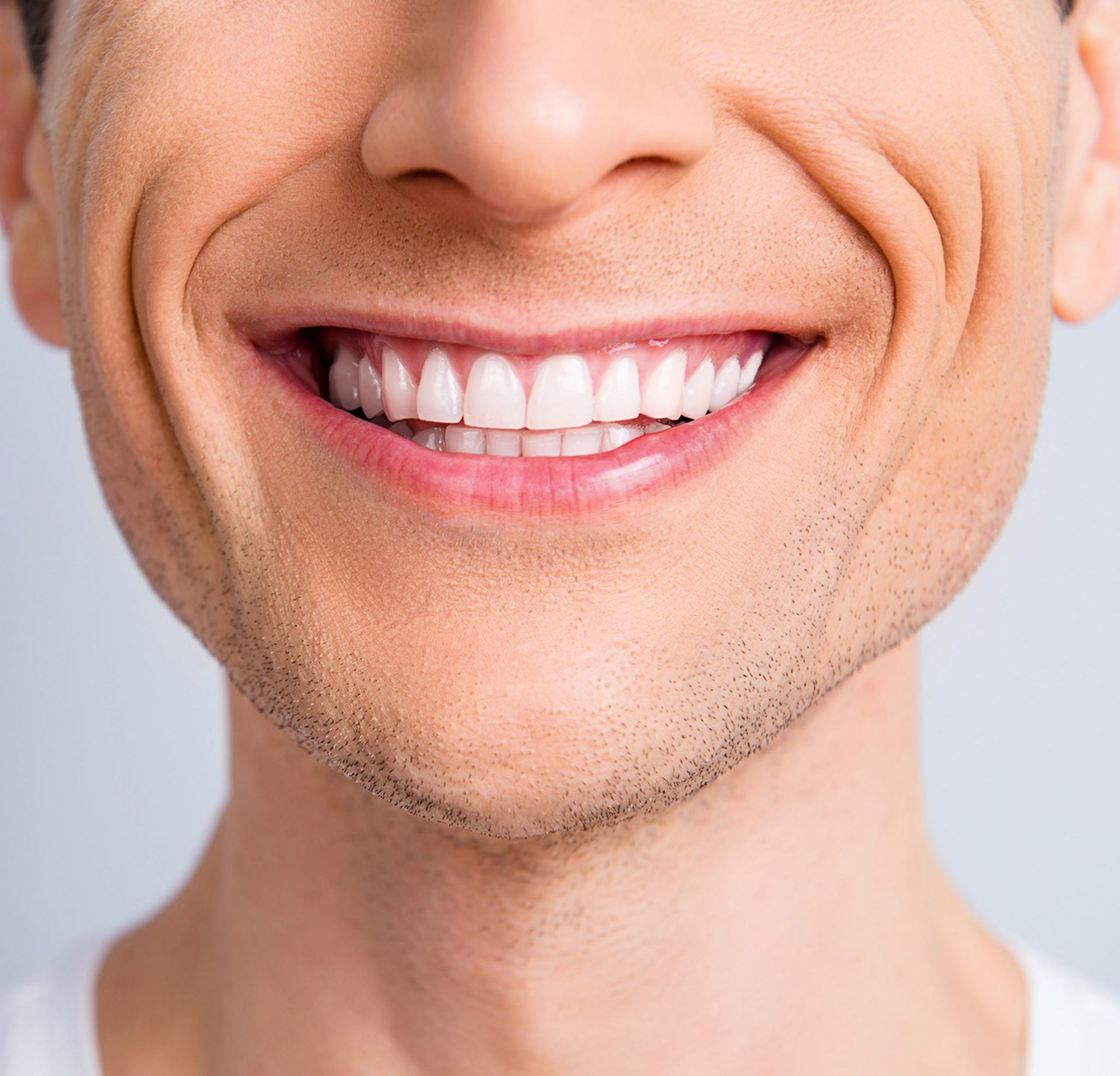 A close up of a man 's smile with white teeth.