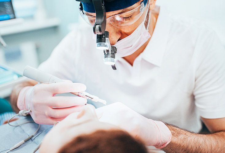 A dentist is examining a patient 's teeth with a magnifying glass.