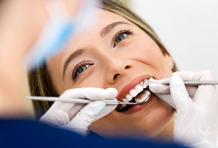 A woman is getting her teeth examined by a dentist.
