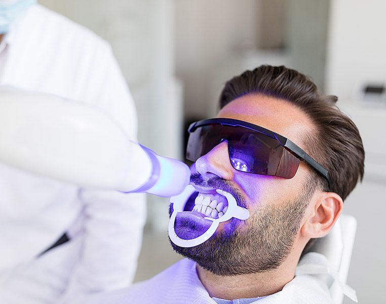 A man is getting his teeth whitened by a dentist.