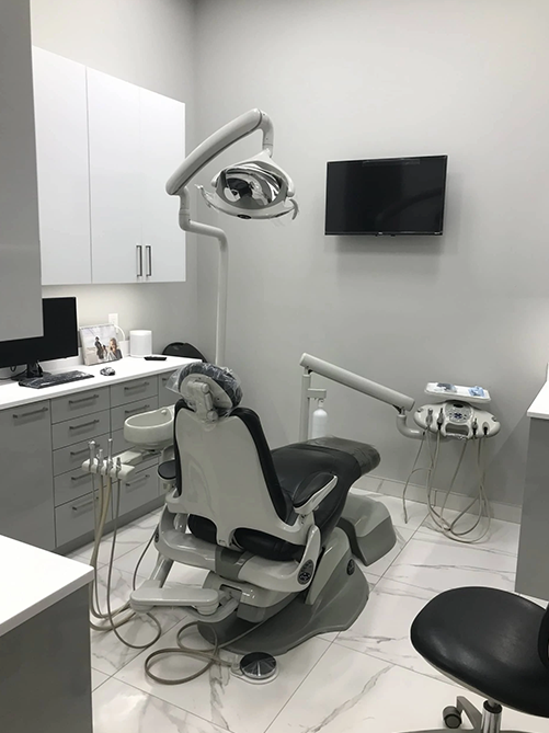 A dental office with a dental chair and a television on the wall.