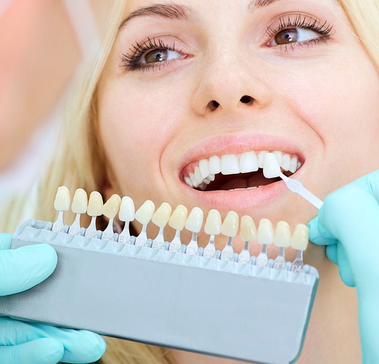 A woman is getting her teeth whitened by a dentist