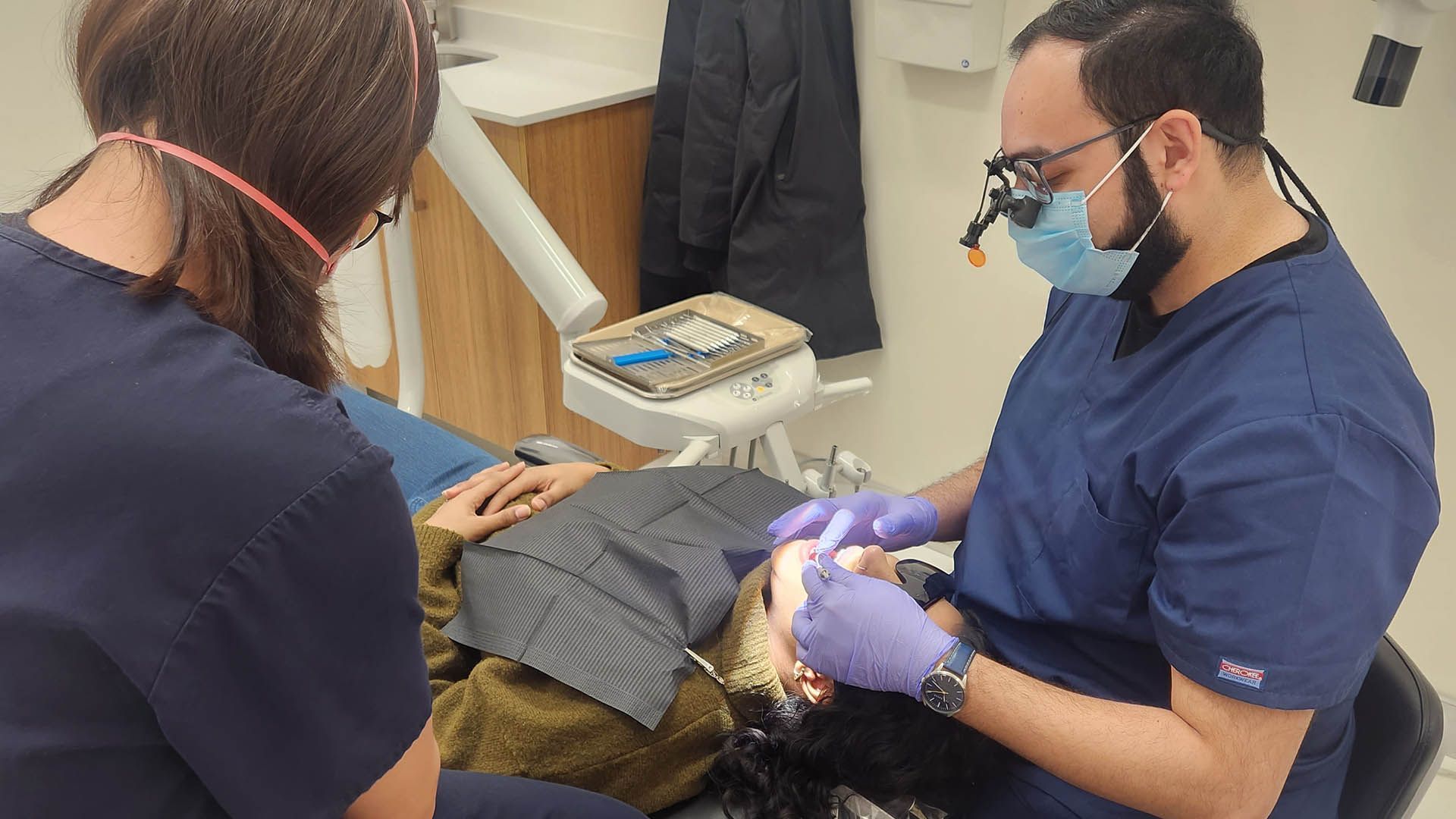 A dentist is examining a patient 's teeth in a dental office.