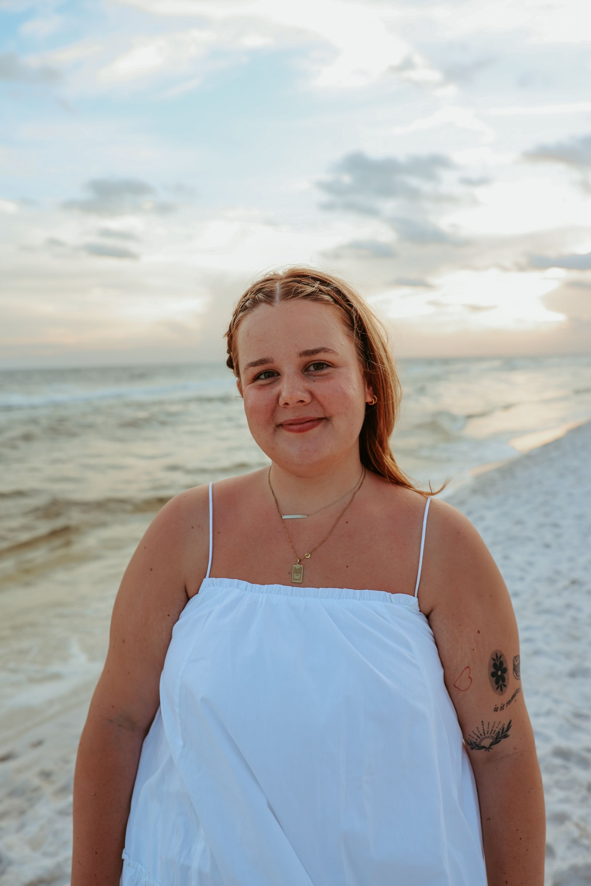 A woman in a white dress is standing on the beach.