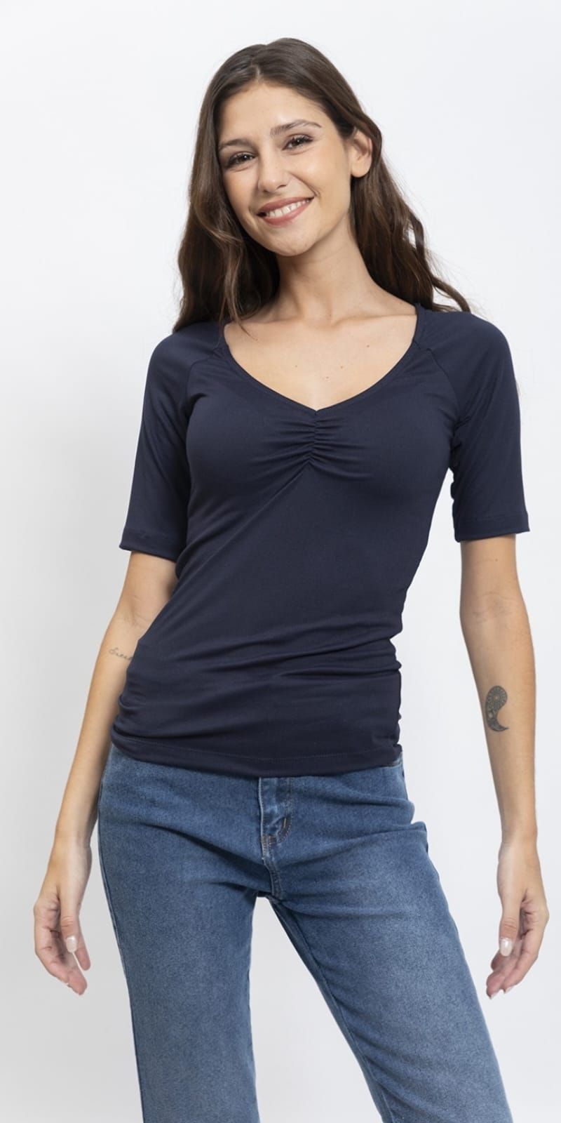 Una mujer lleva una camiseta blanca y jeans azules.