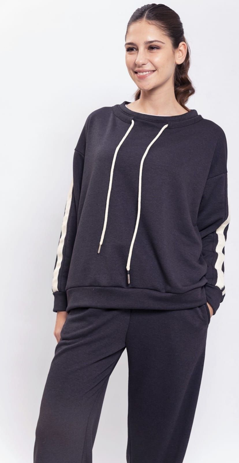 Una mujer lleva una sudadera verde y pantalones de rayas blancas.