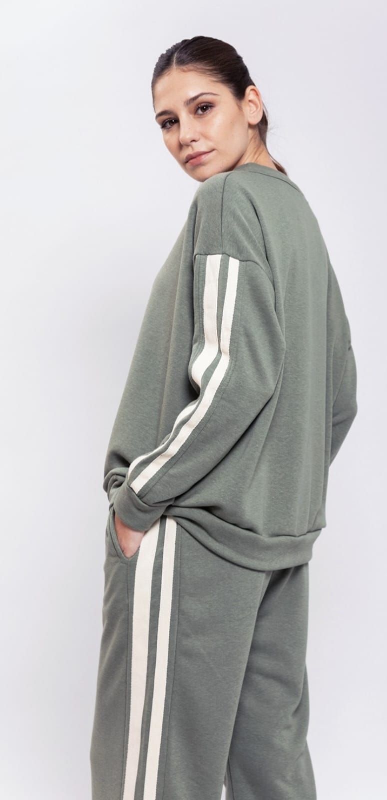 Una mujer lleva una sudadera verde y pantalones de rayas blancas.