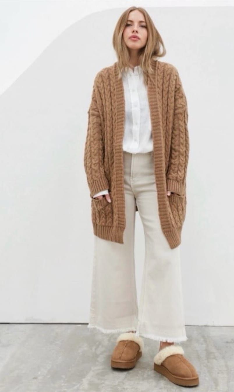 Una mujer lleva un cárdigan marrón con bolsillos.