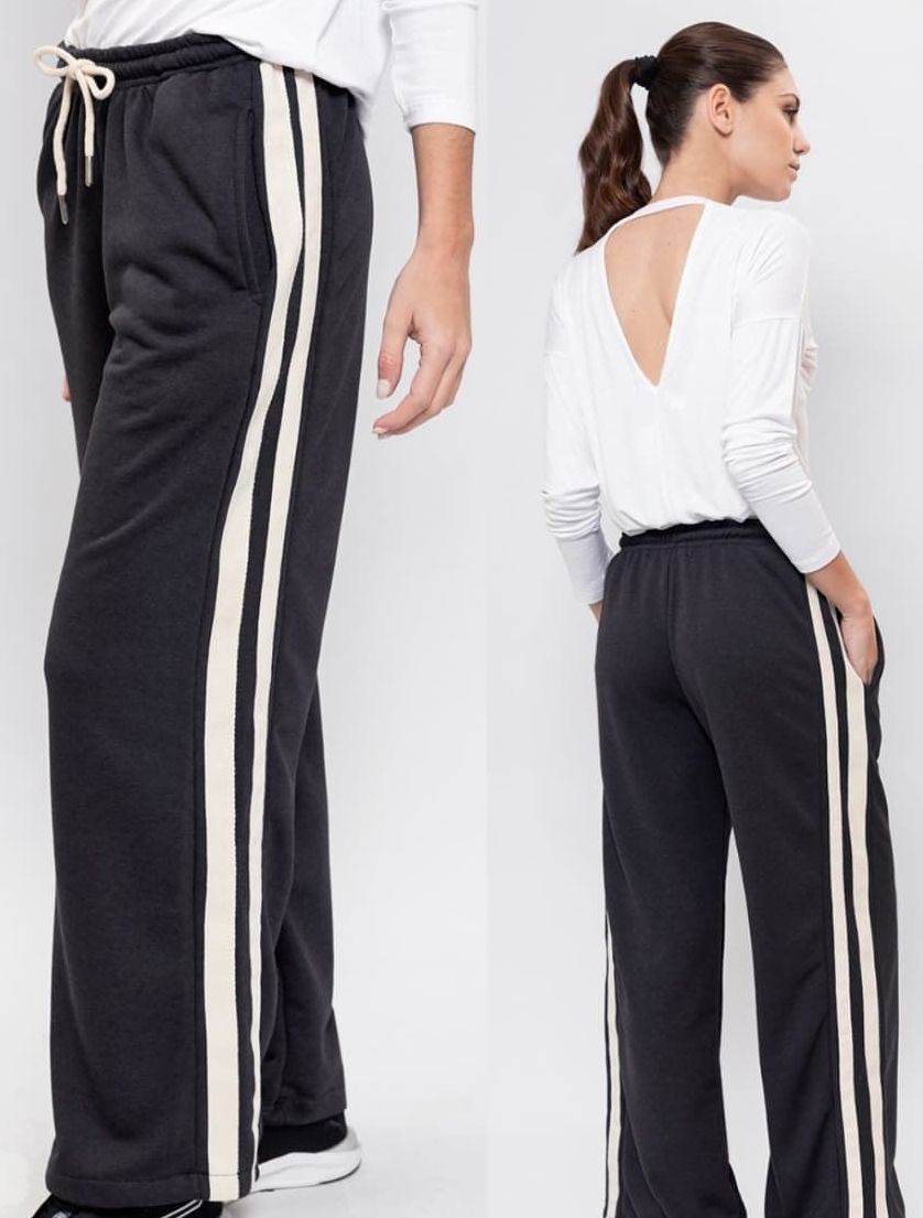 Una mujer que lleva una camiseta blanca y pantalones negros con rayas blancas en los laterales.