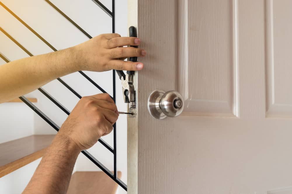 a Person is Fixing a Door With a Screwdriver — Armstrong Locksmiths Ballarat in Ballarat East, VIC