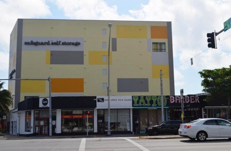 Self-storage building with storefronts on the bottom floor. Yellow, orange, and gray blocks decorate the building facade.