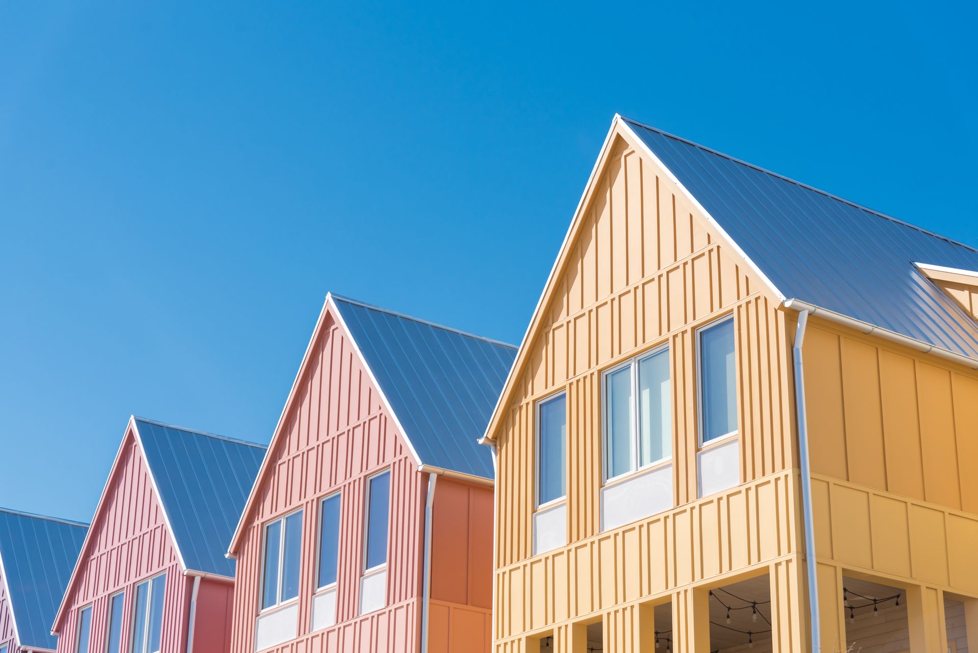Row of colorful houses with pointed roofs against a clear blue sky.
