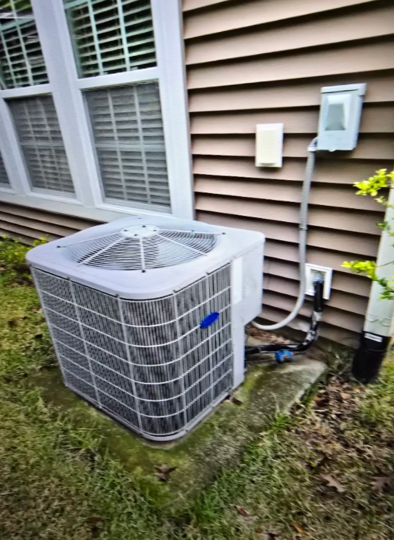 Two air conditioners are sitting on the side of a house.
