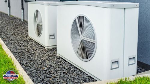 Two white air conditioners are sitting on the side of a building.