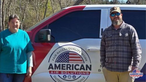 A man and a woman are standing in front of an american air solutions van.