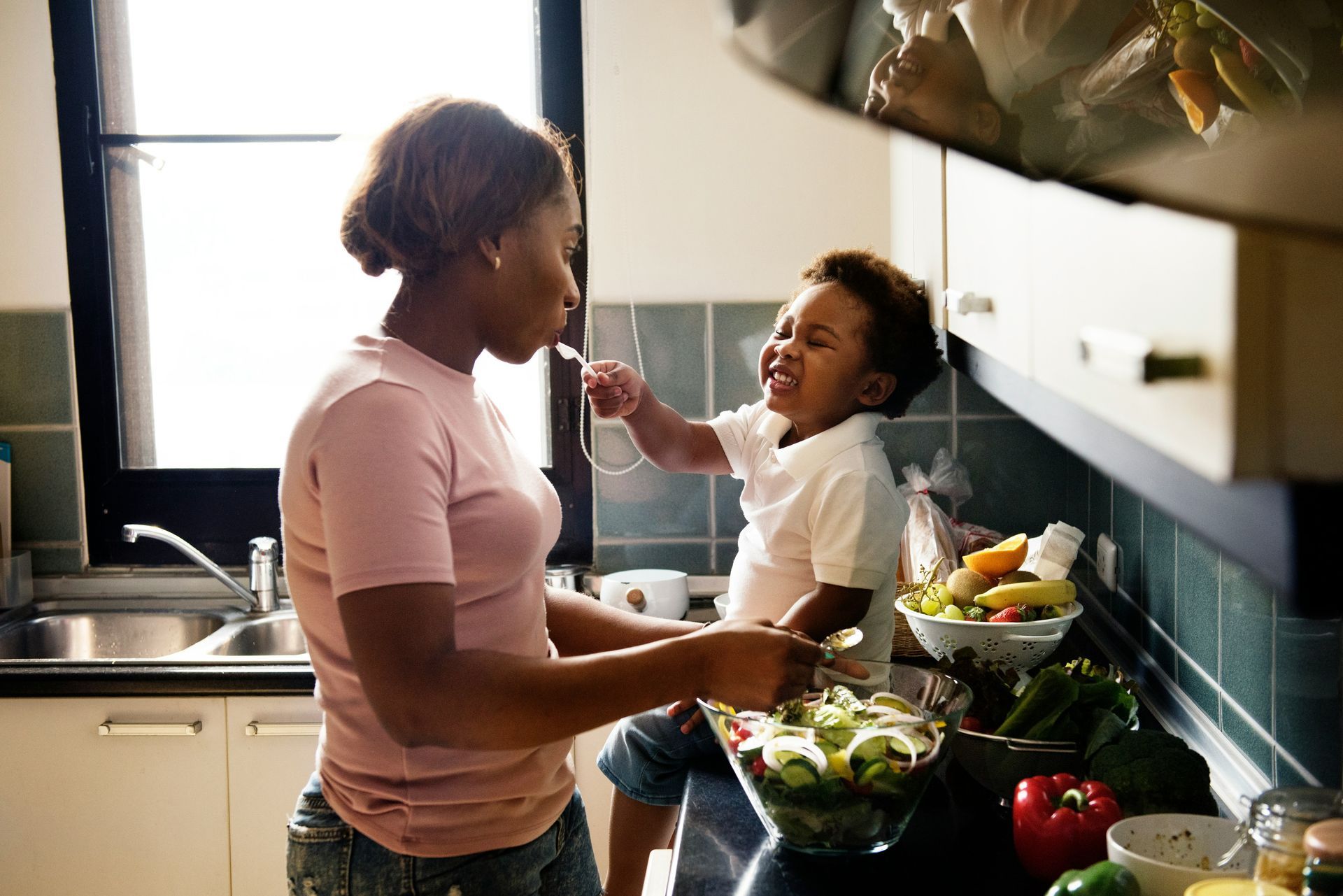 A mother and daughter are washing their hands in a kitchen sink, in Honolulu, HI.