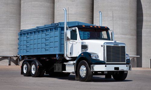 A dump truck is parked in front of a building.