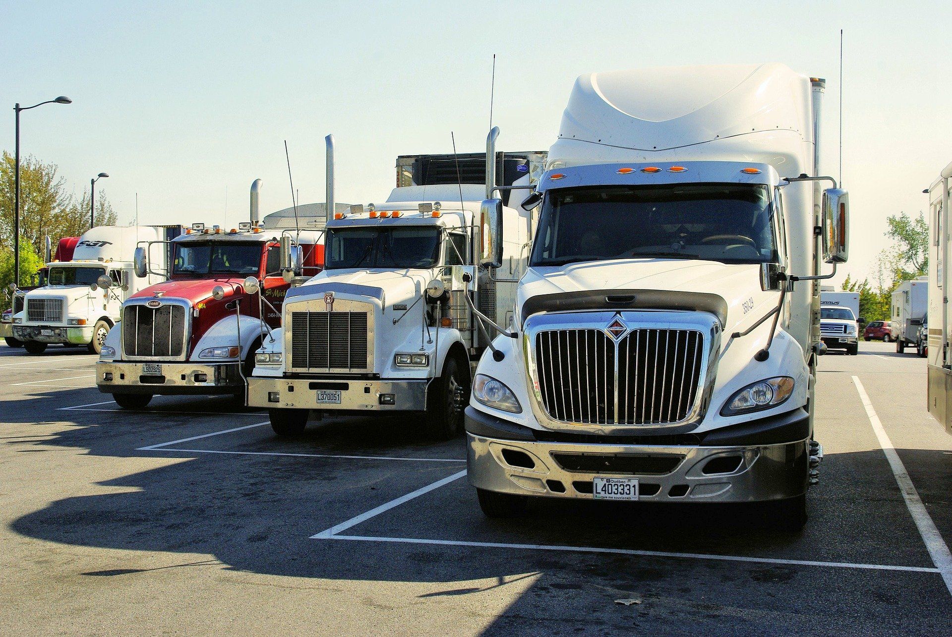 A row of semi trucks are parked in a parking lot.