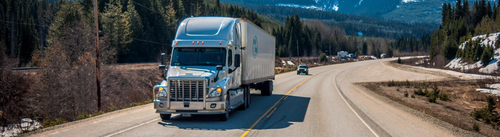A semi truck is driving down a mountain road.