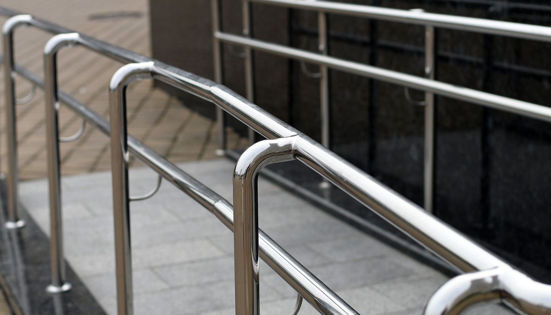 Shiny metal handrails on a ramp, for accessibility.